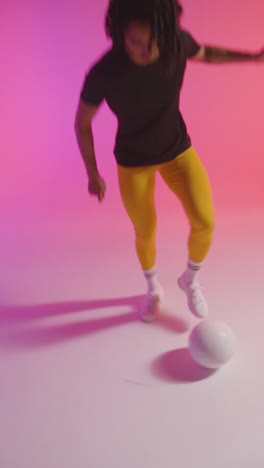 Vertical-Video-Studio-Shot-Of-Female-Footballer-Wearing-Sports-Clothing-Controlling-Ball-With-Feet